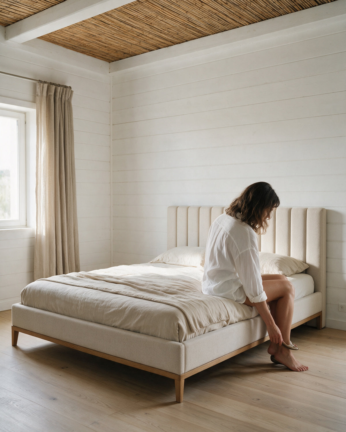ECHO, cama estofada, num quarto na Comporta com uma mulher sentada na beira da cama